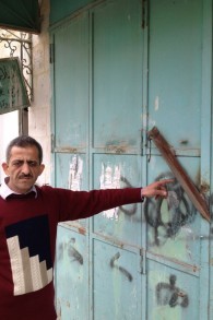 زيدان شرباتي يشير الى دكانه المغلق بقضيب حديدي (بعدسة الحانان ميلر/ طاقم تايمز أوف اسرائيل)