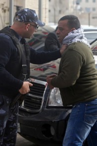 شرطي فلسطيني يوقف أحد المتظاهرين بعد رشق شبان فلسطينيون غاضبون البيض على موكب وزير الخارجية الكندي جون بيرد في رام الله يوم الأحد 18 يناير، 2015    AFP/ABBAS MOMANI