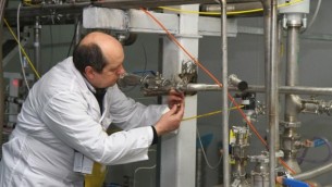 مفتش الوكالة الدولية للطاقة الذرية يقوم بقطع الإتصالات بين أجهزة الطرد المركزي لإنتاح اليورانيوم بنسبة 20% في مفاعل ناتانز النووي جنوب طهران في 20 يناير، 2014. ( Kazem Ghane/IRNA/AFP) 