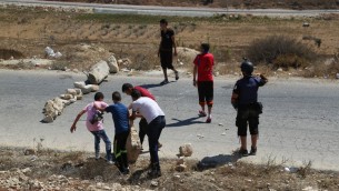 فلسطينيون يستخدمون الصخور لسد شارع في النبي صالح خلال مظاهرة، 28 اغسطس 2015 (Eric Cortellessa/Times of Israel)