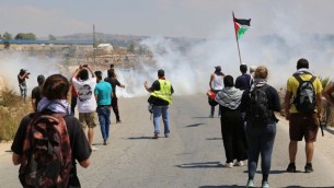 المتظاهرون في النبي صالح في الضفة الغربية يواجهون الغاز المسيل للدموع بعد رشق الجنود الإسرائيليين بالحجارة، 28 اغسطس 2015 (Eric Cortellessa/Times of Israel)