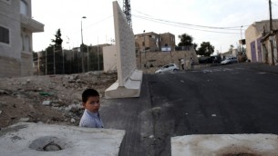 طفل فلسطيني يقف بين حواجز اسمنتية في الشارع وجدار اسمنتي مؤقت يتم نصبه بين حي ارمون هناتسيف اليهودي بمعظمه بالقدس وحي جبل المكبر العربي، 18 اكتوبر 2015 (THOMAS COEX / AFP)