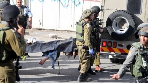 قوات الأمن الإسرائليية تحمل جثمان رجل فلسطيني طعن جندي اسرائيلي قبل قتله بالرصاص في الخليل، 29 اكتوبر 2015 (AFP/Hazem Bader)