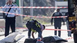 شرطي إسرائيلي يقف بجانب جثة منفذ هجوم فلسطيني الذي قُتل بعد إطلاق النار عليه بعد أن قام بطعن حارسي أمن إسرائيليين في منطقة بركان الصناعية القريبة من مستوطنة أريئيل، 24 ديسبمر، 2015. (Phot by AFP Photo/Jack Guez)