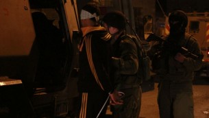 جنود يقتادون معتقل داخل ’زئيف’، وهي مركبة مدرعة لنقل الاشخاص، في قلقيلية، 14 يناير 2016. أمر القائد نمرود كيبولسكي الجنود بنقل المراهق الفلسطيني بعيدا عن اهله قبل تعصيب عينيه وتكبيل يديه، كي لا يراه والده مكبل، قال كيبولسكي (Judah Ari Gross/Times of Israel)