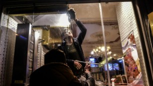 رجلان ينظفان شباك مطعم يقع بالقرب من موقع تفجير انتحاري في شارع استقلال في مركز اسطنبول، 19 مارس 2016 (Bulent Kilic/AFP)
