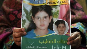 خولة الخطيب تحمل ملصق عليه صورة ابنتها، ملاك، البالغة 14 عاما، والتي حكمت عليها اسرائيل بالسجن شهرين لمحاولتها مهاجة جنود (AFP/Abbas Moman)