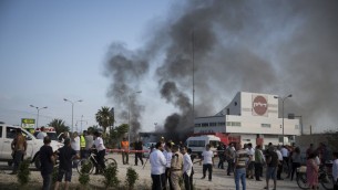 اسرائيليون يشاهدون الدخان يتصاعد من محطة وقود في اسدود اصيبت بصاروخ صادر من قطاع غزة في اليوم الرابع من عملية الجرف الصامد، 11 يوليو 2014 (Hadas Parush/Flash90)