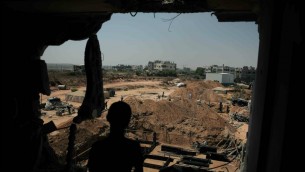 A Palestinian boy looks from his family’s destroyed house at workers rebuilding a house which was destroyed during last summer’s war between Israel and Hamas, as the long-awaited reconstruction began in the Shejaiya neighborhood of eastern Gaza City on Thursday, July 23, 2015. AP Photo/Khalil Hamra
