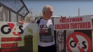 متظاهر يحمل لافتة ضد شركة G4S امام سجن عوفر الإسرائيلي، مايو 2013 (screen capture: YouTube)