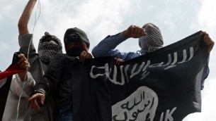 صورة توضيحية لرجال يحملون راية تنظيم الدولة الإسلامية (AFP/Tauseef Mustafa)