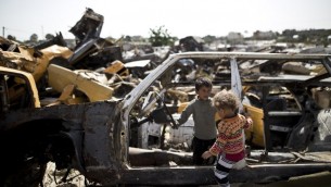 اطفال فلسطينيون يلعبون بين سيارات مهجورة في منطقة فقيرة في مدينة خان يونس، جنوب قطاع غزة، 26 ابريل 2016 (AFP/Mahmud Hams)