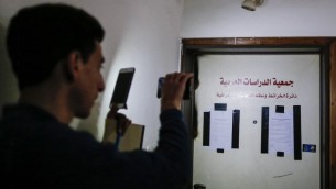 رجل يلتقط صورة بواسطة هاتفه الخليوي لاعلان يبلغ باغلاق مكتب مفترض في بيت حنينا بالقدس الشرقية لمدة ستة اشهر، 13 مارس 2017 (AFP Photo/Ahmad Gharabli)