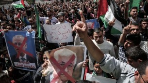 متظاهرون في غزة يحملون صورة مشطوبة لرئيس السلطة الفلسطينية محمود عباس ورئيس الوزراء الفلسطيني رامي الحمد الله في خان يونس، 14 ابريل 2017 (AFP Photo/Said Khatib)
