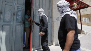 ناشطون في حركة فتح يتحدثون مع صاحب متجر بينما يجولون في شوارع مدينة بيت لحم لمراقبة تطبيق الاضراب العام الذي نادى اليه ناضطون في انخاء الاراضي الفلسطينية والعرب في اسرائيل، دعما للاشرى الفلسطينيين المضربين عن الطعام في السجون الإسرائيلية، 22 مايو 2017 (AFP/Musa AL SHAER)
