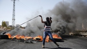 متظاهر فلسطيني يلقي الحجارة بواسطة مقلاع باتجاه قوات الامن الإسرائيلية خلال مواجهات في مستوطنة بيت ايل في الضفة الغربية، 11 اكتوبر 2015 (AFP/Abbas Momani)