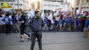 رجل شرطة إسرائيلي يقف حارسا في حين يشارك الإسرائيليين في موكب الفخر السنوي الأول في مدينة بئر السبع جنوب إسرائيل، في 22 يونيو / حزيران 2017. (AFP/Menahem Kahana)