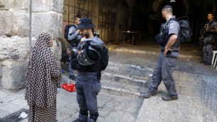 شرطي من حرس الحدود يقوم بالتحقق نت بطاقة هوية سيدة فلسطينية في البلدة القديمة في القدس، 16 يوليو، 2017. (Menahem Kahana/AFP) 