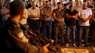 قوات الأمن الإسرائيلية تقف أمام المصلين المسلمين الفلسطينيين الذين يصلون خارج بوابة الأسباط، المدخل الرئيسي لمجمع الحرم القدسي في البلدة القديمة في القدس، في 19 يوليو / تموز 2017. (AFP PHOTO / Ahmad GHARABLI)