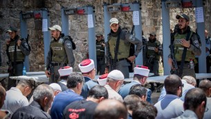 يقود مسؤولو الوقف صلاة المسلمين خارج الحرم القدسي في البلدة القديمة في القدس في 16 يوليو / تموز، مع البوابات الاكترونية في الخلفية. (Yonatan Sindel/Flash90)