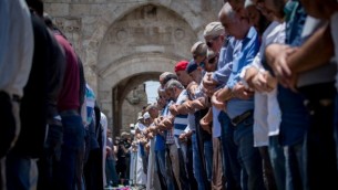 مصلون مسلمون يؤدون صلاة العصر عند باب الأسباط، خارج الحرم القدسي، في البلدة القديمة لمدينة القدس، 19 يوليو، 2017. (Yonatan Sindel/Flash90) 