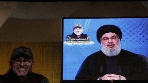 الأمين العام لمنظمة ’حزب الله’ حسن نصر الله يظهر على شاشة عملاقة خلال بث لخطابه في 20 مايو، 2016 في الضاحية الجنوبية للعاصمة بيرت خلال مراسم إحياء ذكرى القيادي في المنظمة مصطفى بدر الدين (الذي يظهر في الصورة) الذي قُتل في هجوم بالمدفعية بالقرب من دمشق. (Joseph Eid/AFP)