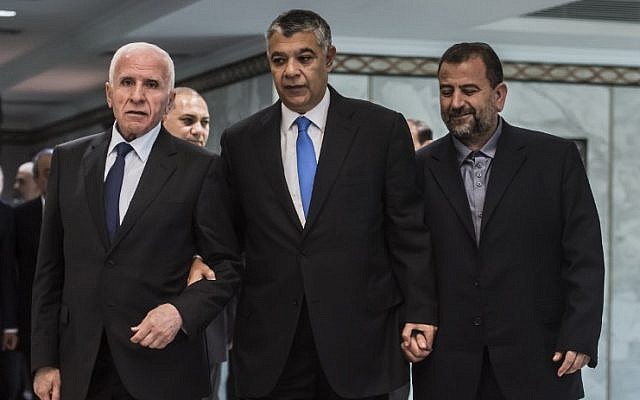 رئيس جهاز المخابرات المصرية خالد فوزي، وسط الصورة، يصل برفقة المسؤول في حركة ’فتح’ عزام الأحمد، من اليسار، والمسؤول في ’حماس’ صالح العاروري، من اليمين، قبل التوقيع على اتفاق المصالحة في القاهرة في 12 أكتوبر، 2017. (AFP/ KHALED DESOUKI)