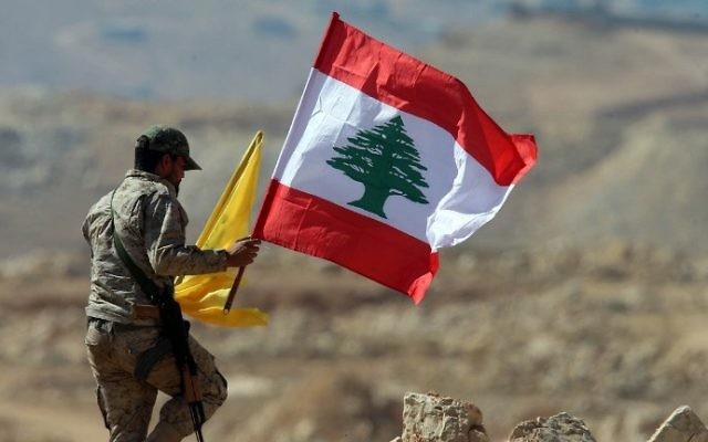 أحد عناصر منظمة "حزب الله" اللبنانية يحمل العلم اللبناني وعلم ’حزب الله’ خلال جولة للصحافيين بالقرب من مدينة عرسال الحدودية، 25 يوليو، 2017. (AFP Photo/Stringer)