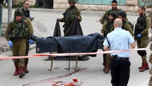 جنود اسرائيليون يحملون جثمان المعتدي الفلسطيني الذي قُتل برصاص جندي اطلق النار على رأسه بينما كان ملقى مصاب على الارض بعد طعنه جندي في الخليل، 24 مارس 2016 (AFP / HAZEM BADER)