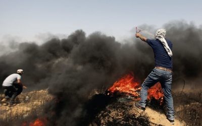 Palestinians hurl stones and burning tires near the Gaza border earlier this month. Photo: AP Photo/Adel Hana