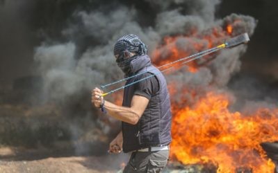 A Palestinian protester uses a sling to hurl stones towards Israeli forces during clashes along the Gaza border. Photo: AAP Image/CrowdSpark/Mhmed Ali