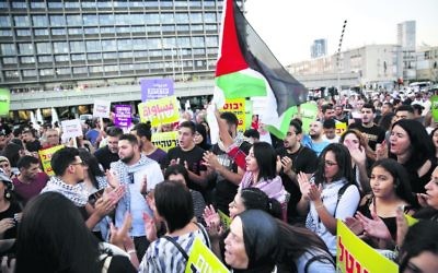 Israeli Arabs hold a Palestinian flag during Saturday's protest against the nation state law in Tel Aviv. Photo: AP Photo/Ariel Schalit
