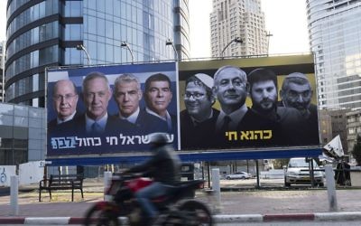 An Israeli motorcyclist passes billboards put up by the Blue and White
alliance featuring their candidate for prime minister, Benny Gantz, alongside
his fellow party leaders next to a panel showing Benjamin Netanyahu and
extreme right-wing politicians. On the right side the Hebrew translates as
“Kahane lives” and on the left reads, “People of Israel live Blue and White”. Photo: EPA/Jim Hollander