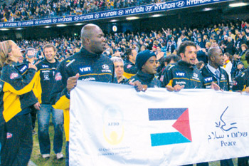   The Peace Team carrying a banner with both the Palestinian and Israeli flags at the Telstra Dome in Melbourne. 