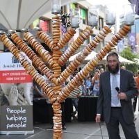 Rabbi Mendel Kastel with his doughnut menorah for Jewish House in Bondi Junction. There were more than 300 doughnuts used to make the 2-metre tall menorah that was lit in front of 500 people. Photo: Henry Benjamin Rabbi Mendel Kastel with his doughnut menorah for Jewish House in Bondi Junction. There were more than 300 doughnuts used to make the 2-metre tall menorah that was lit in front of 500 people. Photo: Henry Benjamin