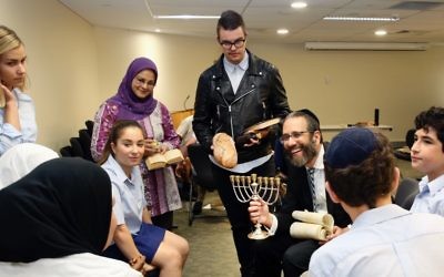 Rabbi Zalman Kastel explains Chanukah to a group of students as teachers Grace Smith, Zohra Aly and Jaxon Jennings look on.
Photo: Noel Kessel
