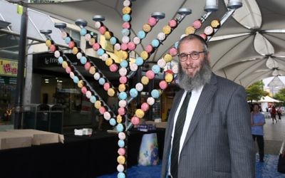 Rabbi Mendel Kastel next to the giant cupcake menorah at Jewish House's Chanukah party in Bondi Junction. Photo: Noel Kessel