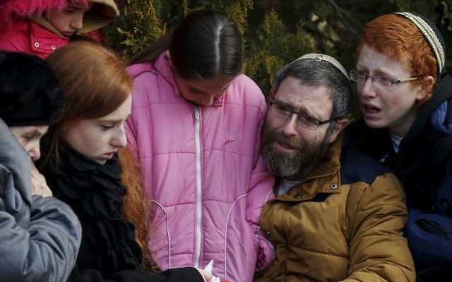 The husband and children of Dafna Meir mourn during her funeral ceremony in Otniel.