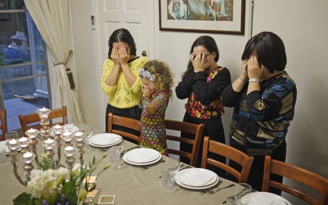 Rebbetzin Laya Slavin prays on a Friday evening with her daughters. Photo: D-Mo Zajac.