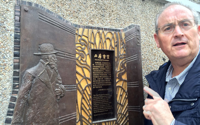 Walt Secord next to an Ohel Rachel Synagogue plaque.