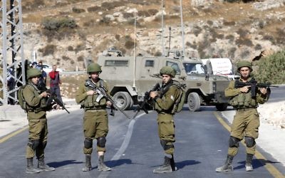 Cap: Israeli soldiers near the scene of Saturday's attack in Hebron. 
Photo: EPA/Abed Al Hashlamoun.
