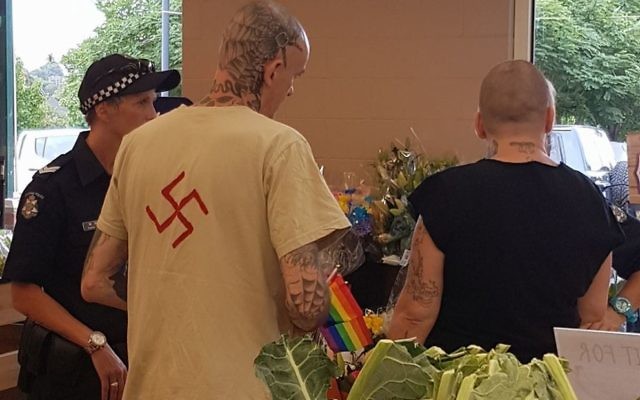 A man wearing a shirt with a swastika symbol is talked to by police at the 2017 Chill-out LGBTQI festival in Daylesford last weekend.