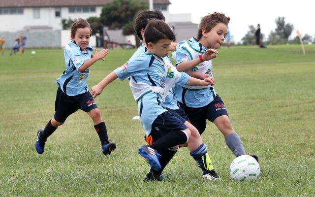 Maccabi Junior FC players race for the ball in their opening match at Christison Park. Photo: Noel Kessel