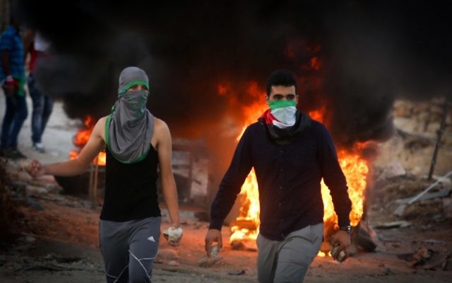 Palestinian protesters throw stones and burn tires during clashes with Israeli security forces in the West Bank,in September 2015.
Photo: JTA/ FLASH90