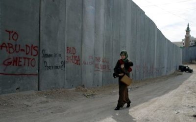 A Palestinian woman carries her child past the security barrier near the village of Abu Dis.
Photo: Brian Hendler/JTA