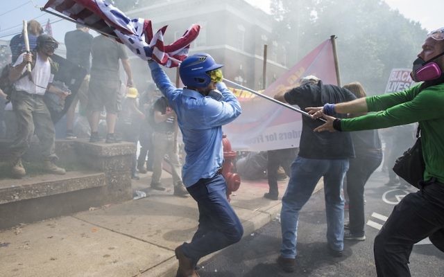 CHARLOTTESVILLE, USA - August 12: A white supremacist trying to strike a counter protestor with a white nationalist flag during clashes in Charlottesville.
Photo: Samuel Corum/Anadolu Agency/Getty Images.