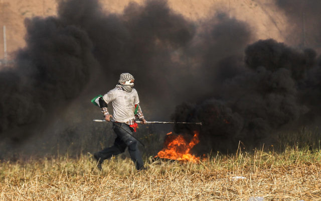 A Palestinian protester burning tyres during clashes with Israeli forces near the Gaza border. Photo: Said Khatib/AFP/Getty Images