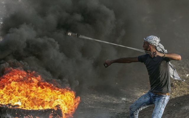 A Palestinian protester uses a slingshot to throw stones during clashes near the border last Friday. Photo: EPA/Mohammed Saber