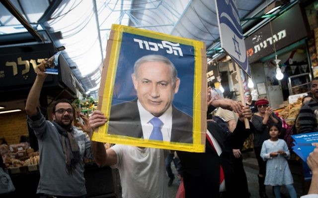 A Likud party supporter holds a picture of Israeli Prime Minister Benjamin Netanyahu at the Mahane Yehuda market in Jerusalem, April 7, 2019. (Yonatan Sindel/Flash90)