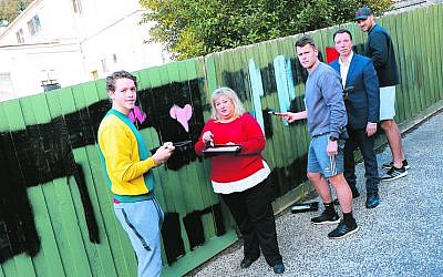 From left: Riley Collier-Dawkins, Aliza Shuvaly, Maverick Weller, Dvir
Abramovich and Toby Nankervis cover antisemitic graffiti on a fence at Aliza’s
Place Cafe in Chadstone. Photo: Peter Haskin